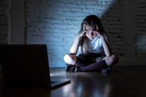 Scared sad girl bullied on line with laptop suffering cyberbullying and harassment feeling desperate and intimidated. Child victim of bullying stalker social media network - MySociaLife - MySociaLife